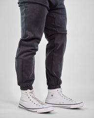 HyperCool sweatpants in dark gray with strategic perforation and elastic cuffs, paired with white sneakers for a sporty look.