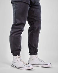 HyperCool sweatpants in dark gray with strategic perforation and elastic cuffs, paired with white sneakers for a sporty look.
