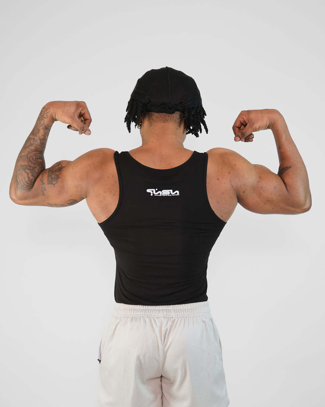 Man flexing muscles in a tight-fit black Atlas Tank made from breathable bamboo viscose.