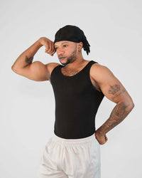 Model showcasing a black tank top, emphasizing a tight fit and muscular physique, perfect for workouts.