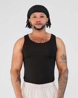 Man wearing a black Atlas Tank top, showcasing a tight fit and emphasizing physique, suitable for exercise.