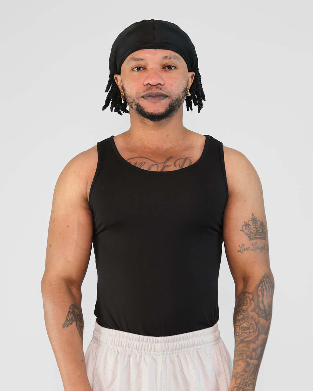 Man wearing a black Atlas Tank top, showcasing a tight fit and emphasizing physique, suitable for exercise.
